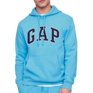 A person is wearing a light blue GAP hoodie with a front pocket and drawstrings. The hoodie features the brand's logo prominently in large, bold letters on the front.