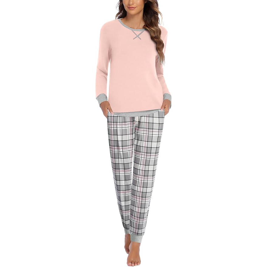 A woman is wearing a pink long-sleeve pajama top with a crisscross neckline and grey cuffs, paired with checkered pajama pants.