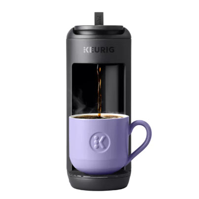 A Keurig coffee maker brews coffee into a purple mug.