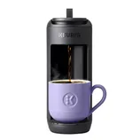 A Keurig coffee maker brews coffee into a purple mug.