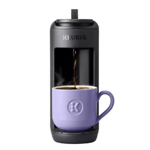 A Keurig coffee maker brews coffee into a purple mug.
