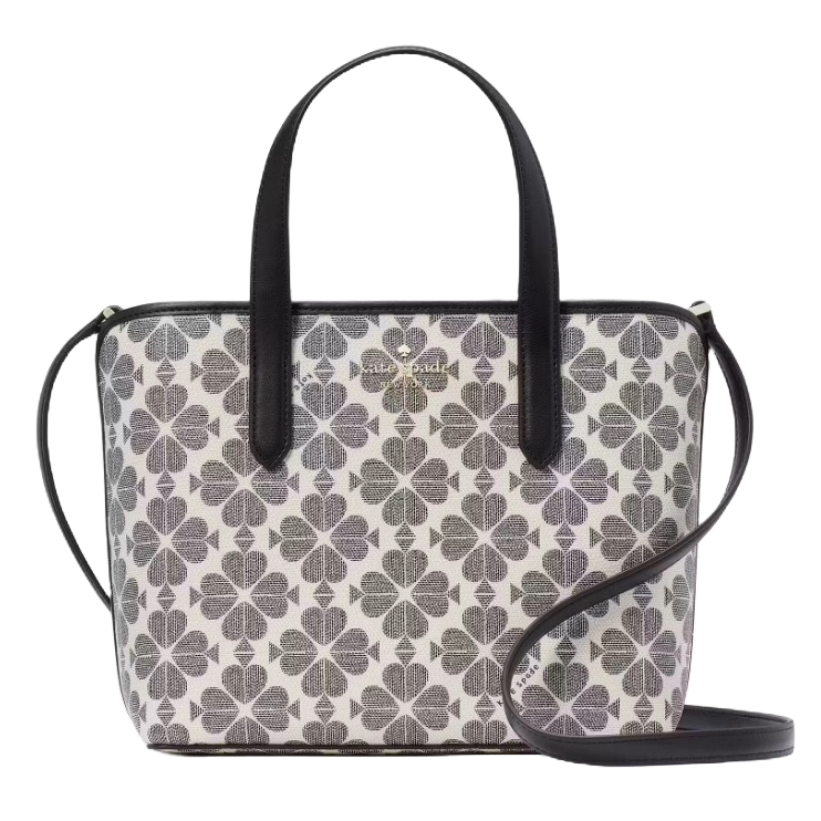 A handbag featuring a black and white clover pattern with dual top handles and a detachable crossbody strap.