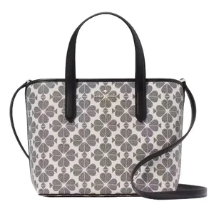 A handbag featuring a black and white clover pattern with dual top handles and a detachable crossbody strap.