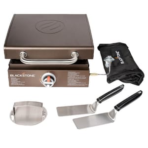 Blackstone 17\“ Griddle with a 12,500 BTU output includes a tool kit featuring two stainless steel spatulas, a protective griddle cover, and a grill carry bag for convenient transport.