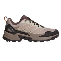 A beige and brown Adidas Terrex hiking shoe with a rugged sole and orange pull tab, designed for outdoor activities.