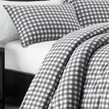 Gray and white checkered bedding set with pillowcases and a comforter on a neatly made bed.