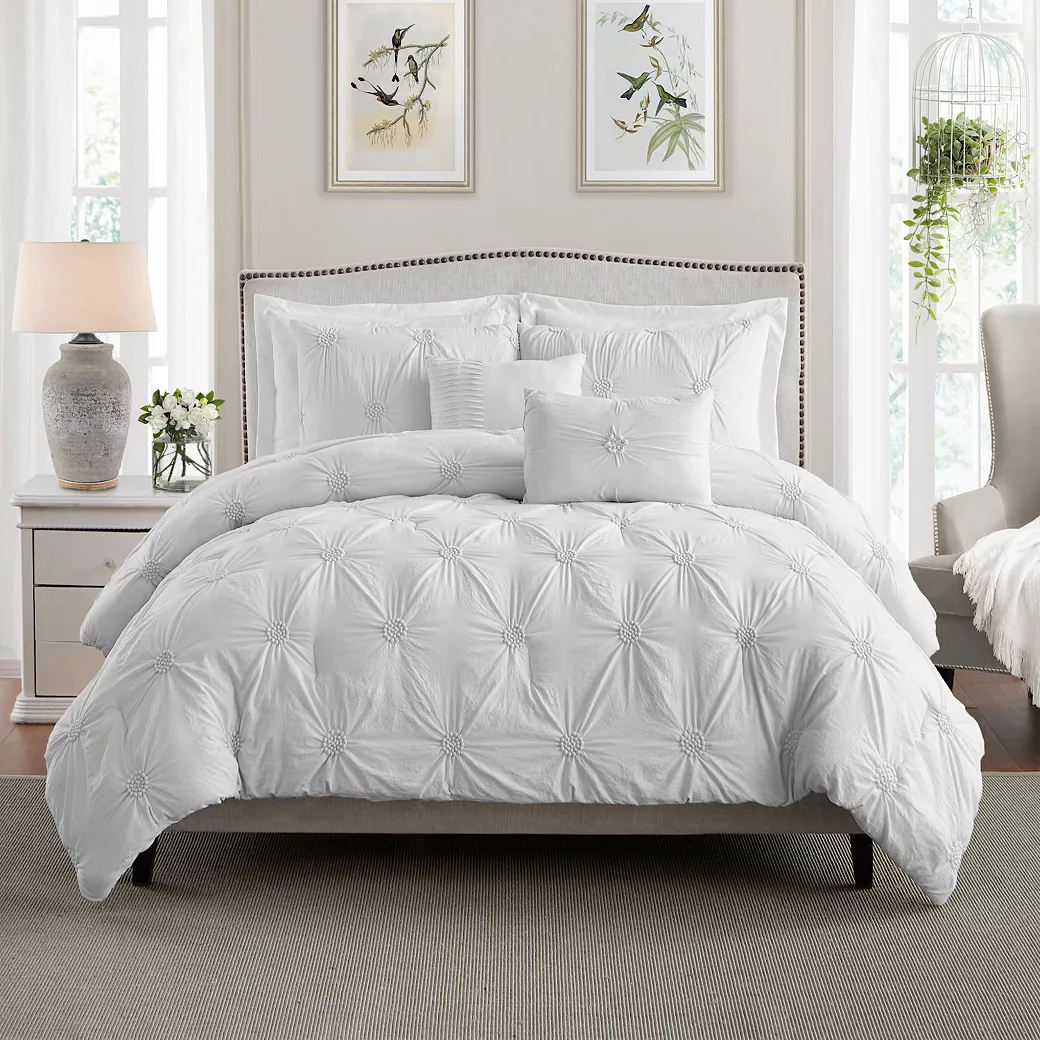 This is a white pintuck comforter set featuring a decorative pattern of raised, pinched fabric in a symmetrical design, complete with matching pillow shams.