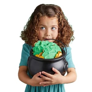 A child holds a black cauldron filled with green and gold treats, likely candies or cookies.