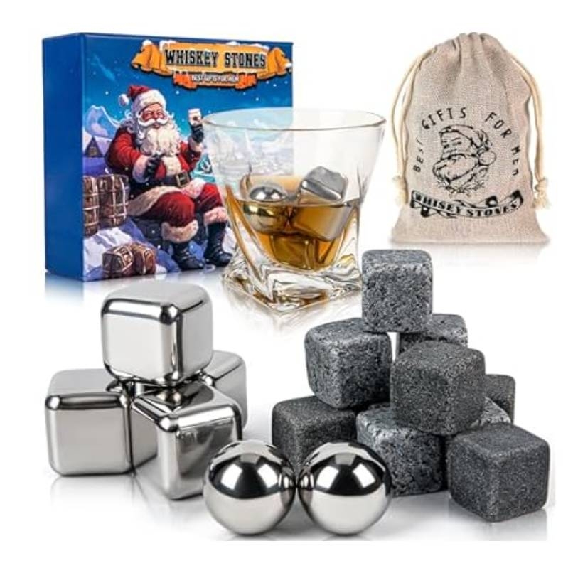 A set including whiskey stones in stainless steel and stone finishes, a glass of whiskey with stones inside, a gift box with Santa imagery, and a drawstring storage pouch.
