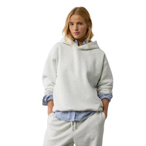 A white, oversized Henley hoodie paired with a blue and white striped shirt underneath. The hoodie has a relaxed fit with dropped shoulders and is styled with matching sweatpants.