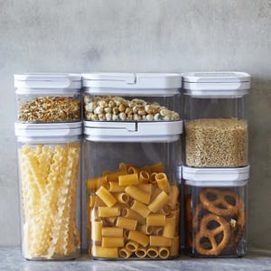 A 20-piece dry food storage set featuring transparent, airtight containers with white lids, organized neatly with contents like pasta, grains, snacks, and seeds visible inside.
