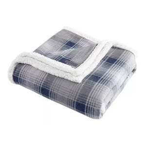 A folded, plaid-patterned gray and blue sherpa fleece blanket with a soft, white fluffy lining along the edges.