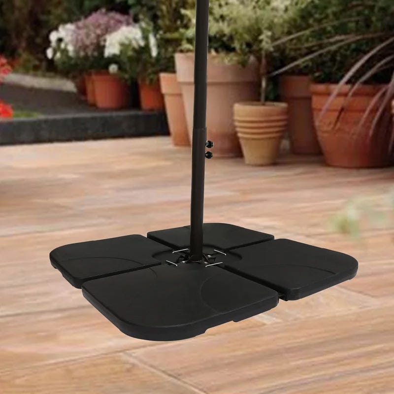 A set of four black, interlocking, curved counterweights designed to stabilize an outdoor umbrella base, placed on a wooden patio floor.