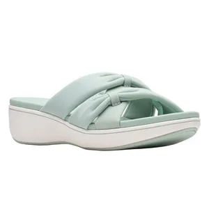 A light green slide sandal with a crisscross strap design and a thick white sole.