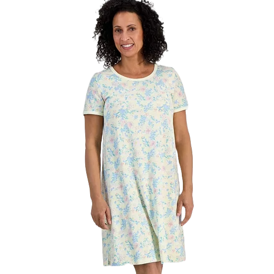 A woman is wearing a short-sleeve, knee-length dress with a pastel floral pattern. The dress has a round neckline and a relaxed fit.