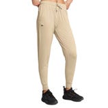 Beige joggers with a drawstring waist and side pockets, featuring a small logo, paired with black athletic shoes.