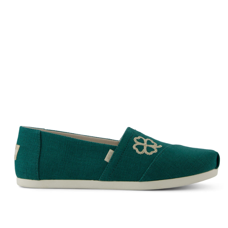 Teal slip-on shoe with a simple canvas design, featuring a decorative embroidery on the upper and a white rubber sole.