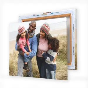 A canvas print displays a family of four enjoying a day at the beach, with two children and two adults wearing winter clothing, smiling and embracing each other.