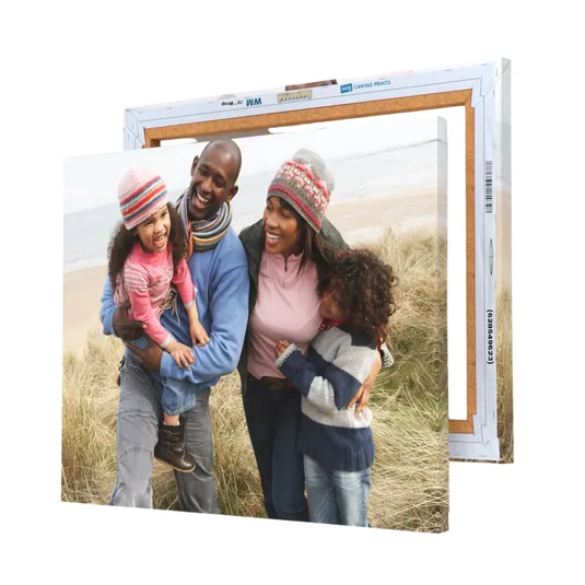 A canvas print displays a family of four enjoying a day at the beach, with two children and two adults wearing winter clothing, smiling and embracing each other.