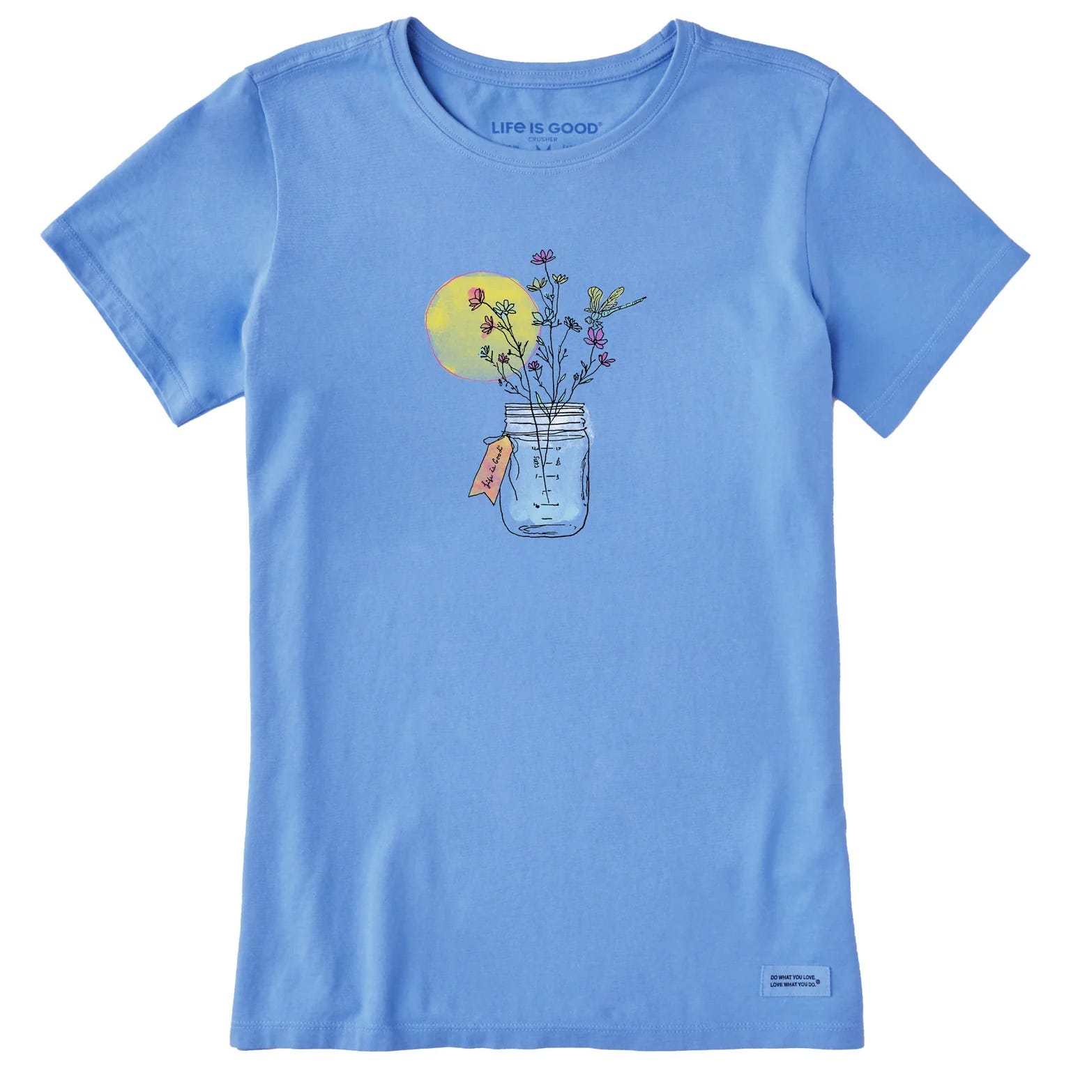 Blue T-shirt featuring a jar of flowers graphic with a yellow sun behind. Above the graphic, \“LIFE IS GOOD\“ is printed.