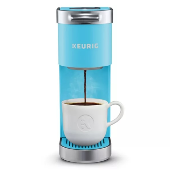 A light blue Keurig coffee maker brewing coffee into a white mug.