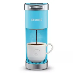 A light blue Keurig coffee maker brewing coffee into a white mug.