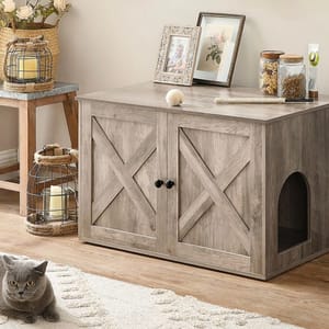 A wooden cabinet with dual doors serves as a cat litter box cover, featuring an arched entry on the side. It is accessorized with decorative items and a resting cat nearby.