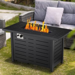 Black propane fire pit table with a rectangular design, featuring an adjustable flame and control knobs, set outdoors next to rattan patio furniture with cushions.
