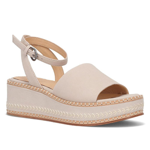 The Frye Joy Ankle Sandals feature a beige leather upper with an ankle strap and buckle closure. They have a platform wedge sole with decorative stitching around the edges, providing a stylish yet comfortable design.