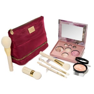The Complete Baked Starter Kit includes a red zippered makeup bag, a palette with various baked powders, four makeup brushes with white and gold handles, and a separate round compact with additional baked powder.