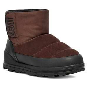 UGG Klamath Mini Suede Classic Boots feature a brown, quilted suede upper, black rubber lower portion, and a durable, treaded sole for traction. They have \“UGG\“ branding on the side of the ankle.