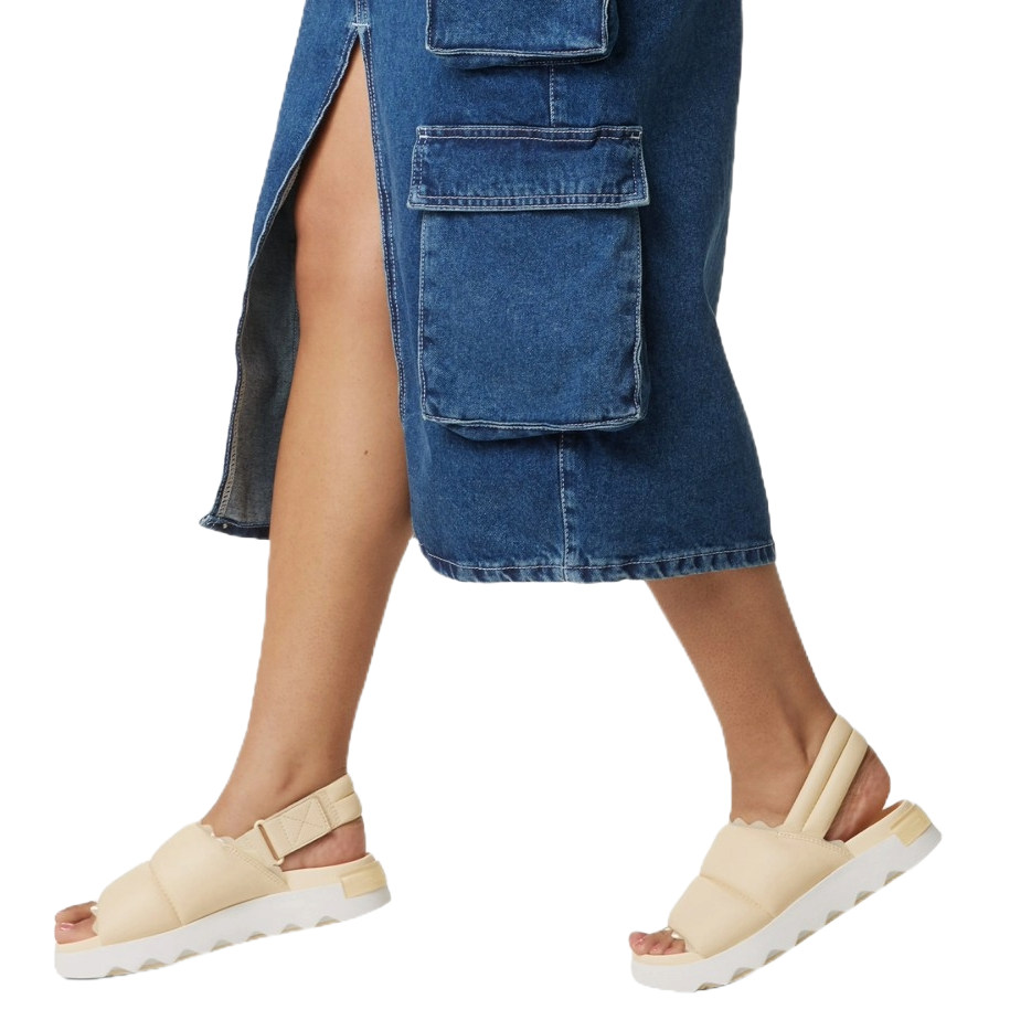 A person is wearing a denim skirt with cargo pockets and beige open-toe sandals with thick straps and a white sole.