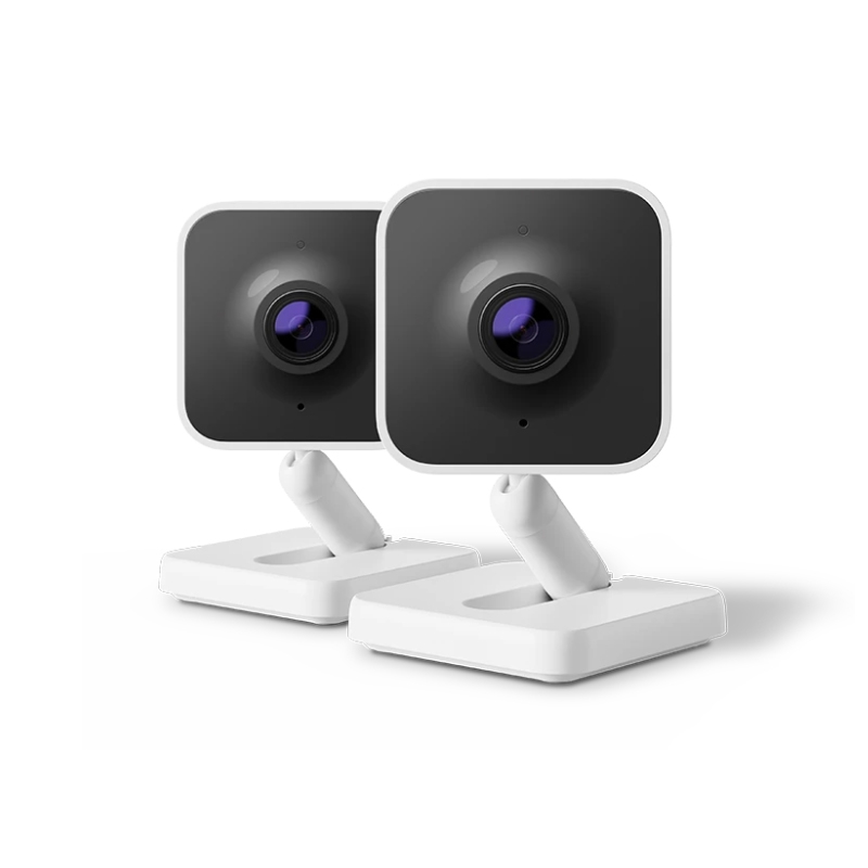 Two Roku Indoor Cameras with a sleek, modern design featuring a black front and a white adjustable base. They have a square shape with a prominent lens in the center.