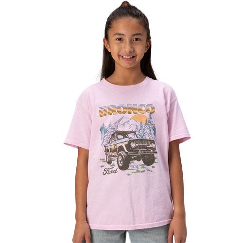 A child wearing a pink T-shirt featuring a vintage Ford Bronco graphic with mountains in the background.