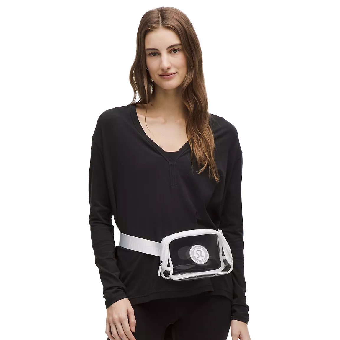 A person wearing a black long-sleeve top and black pants, with a transparent belt bag featuring a logo, worn around the waist.