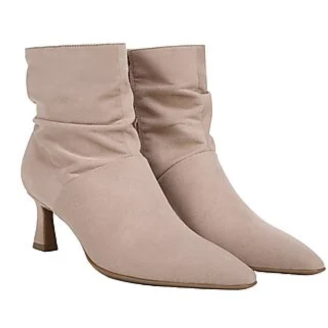 A pair of beige, mid-heel, pointed-toe ankle boots with a slouched design.