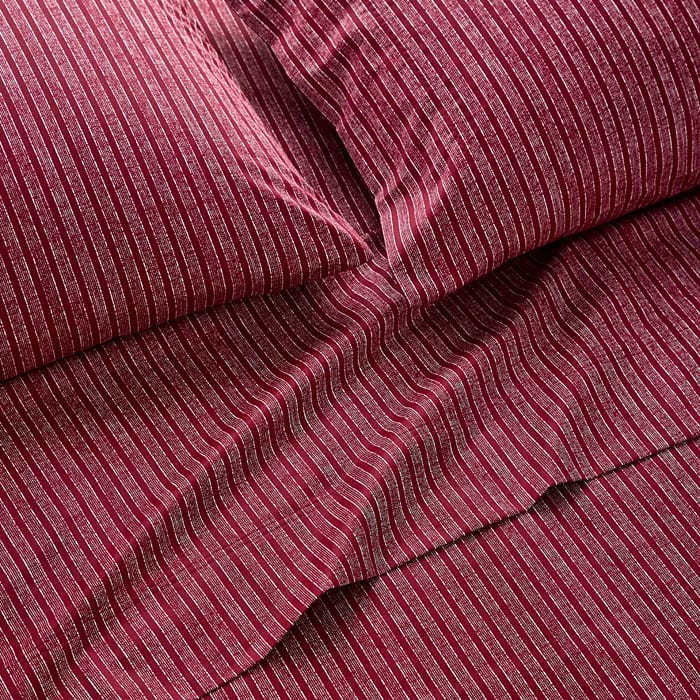 A set of dark red bedding with thin, vertical white stripes, including a flat sheet and pillowcases.