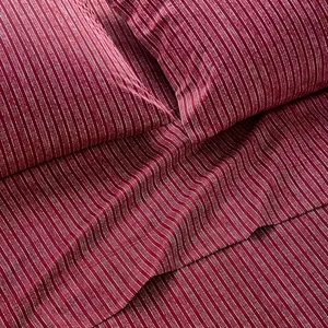 A set of dark red bedding with thin, vertical white stripes, including a flat sheet and pillowcases.
