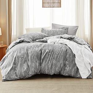A queen-size comforter set with a floral snowflake pattern in gray shades, including two matching pillow shams. The set is displayed on a bed in a room with neutral decor.