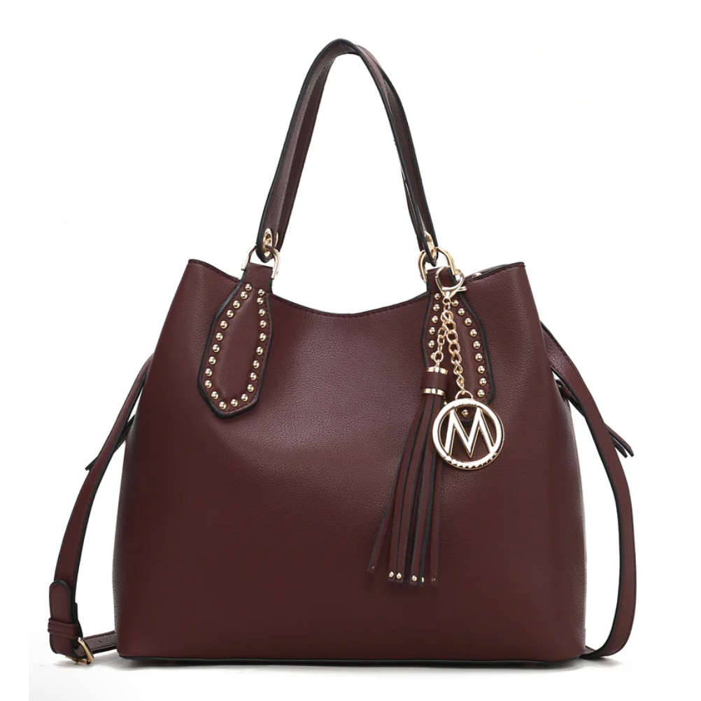 Rich brown shoulder bag featuring gold stud accents on the handles, a decorative gold chain with tassel, and a round \“M\“ charm. Equipped with adjustable strap, suitable for versatile use.