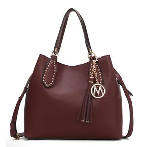 Rich brown shoulder bag featuring gold stud accents on the handles, a decorative gold chain with tassel, and a round \“M\“ charm. Equipped with adjustable strap, suitable for versatile use.