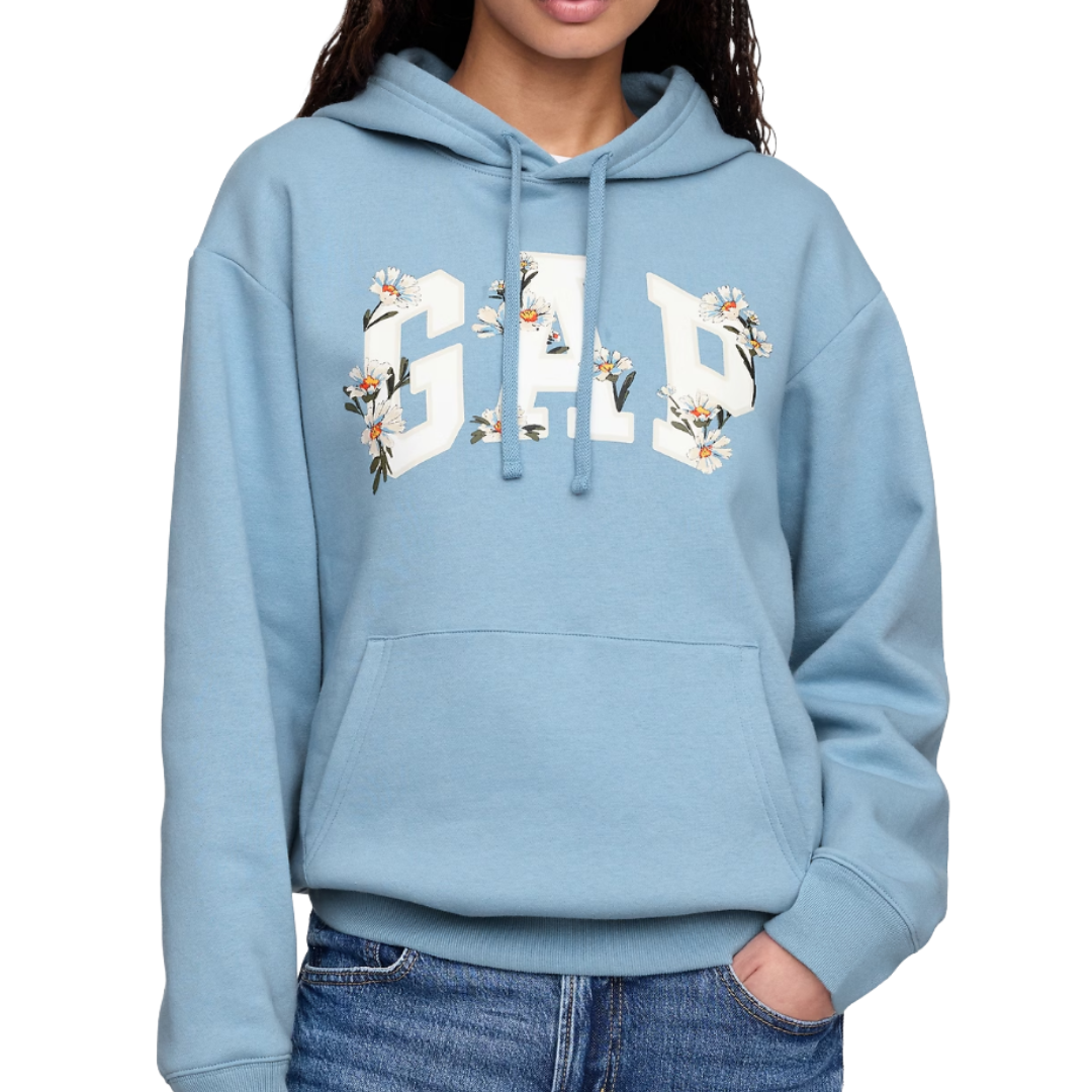 A blue hoodie featuring the GAP logo embellished with floral designs on the letters, paired with denim jeans.