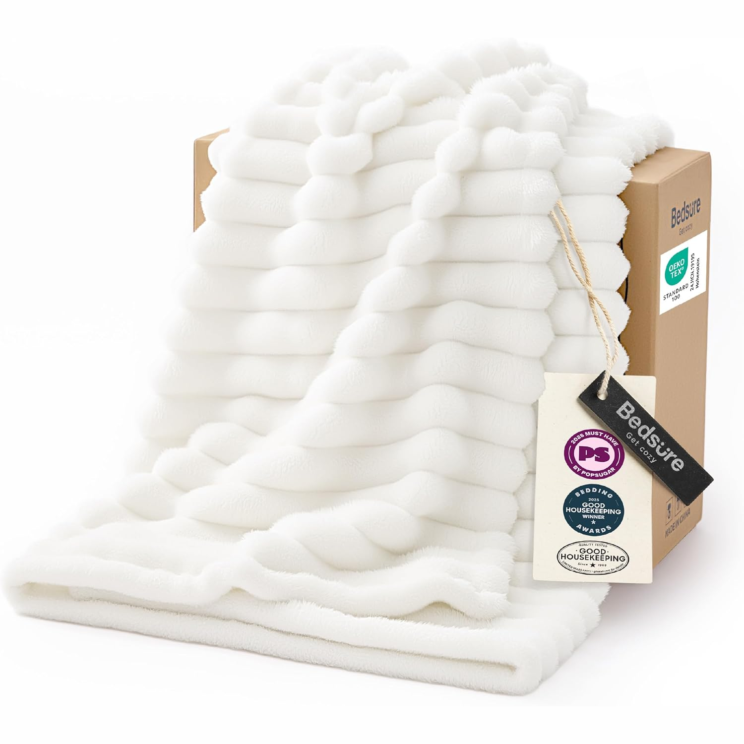 White textured blanket draped over a box, featuring a tag indicating it is from Bedsure, with OEKO-TEX certification and awards like PopSugar's Must Have and Good Housekeeping's Winner.