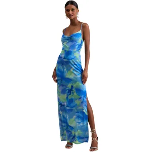 A sleeveless blue and green floral print maxi dress with a cowl neckline, side slit, and thin straps, paired with silver strappy heels and pearl drop earrings.