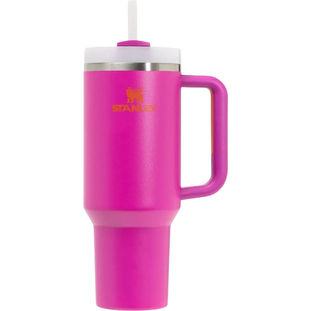 A bright pink Stanley travel mug with a handle and straw, featuring a wide base and stainless steel rim.