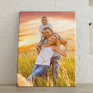 Large canvas print of a happy family in a field during sunset, leaning against a white brick wall.