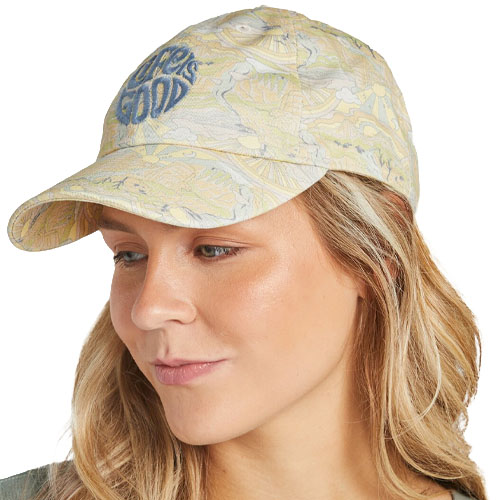A woman wears a light-colored patterned baseball cap with \“Life is Good\“ embroidered on the front.