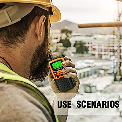 A man wearing a hard hat is holding an orange and black walkie-talkie with a digital display and buttons, demonstrating its use in an industrial setting.