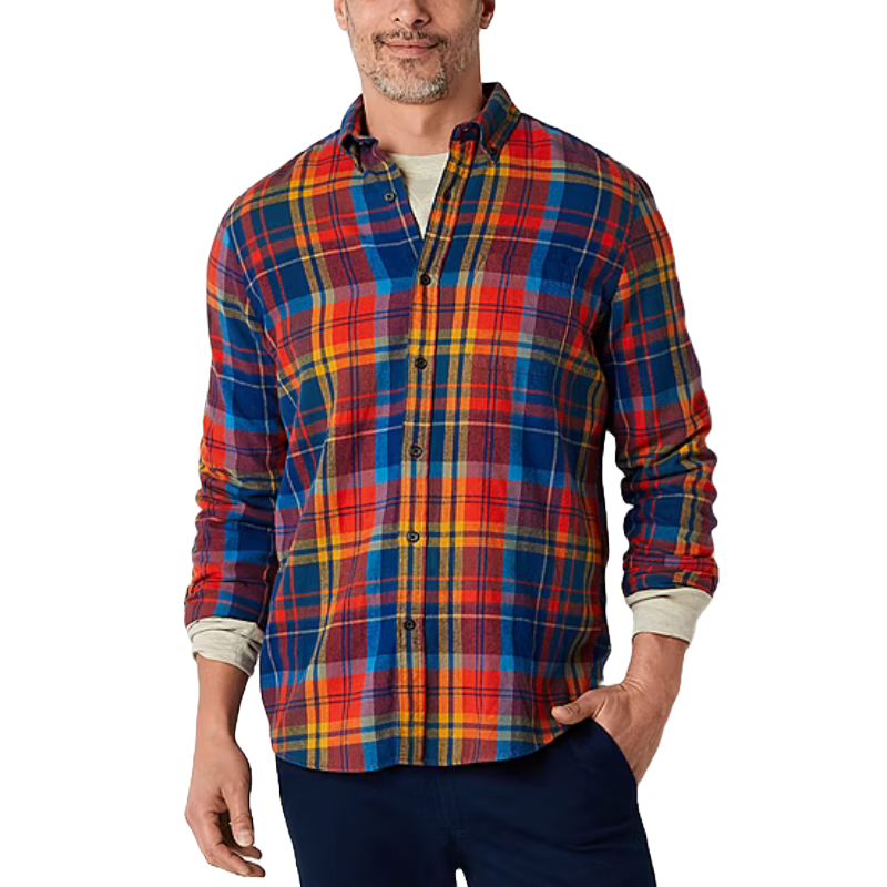 A man wearing a colorful, plaid flannel shirt with blue, red, and yellow patterns, paired with dark pants.