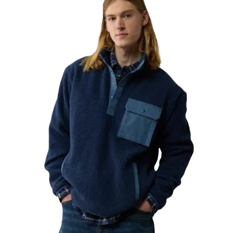 A man is wearing a blue sherpa jacket with a chest pocket and contrasting trim on the collar, pocket, and sleeve cuffs.